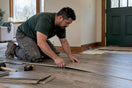 Installer fitting a floating floor in a home